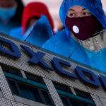 Trabalhadora chinesa com máscara em uma fábrica da Foxconn