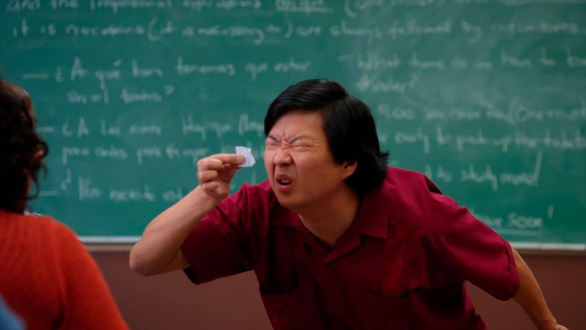 Ator Ken Jeong faz esforço para ler algo em um pedacinho de papel