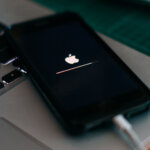 Foto de um iPhone ligado ao cabo com a tela preta e o logo da maçã